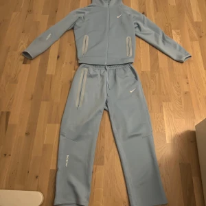 Ljusblå träningsset från NOCTA - Säljer ett stilrent ljusblått träningsset från NOCTA. Kollaboration emellan Nike och rapp artisten Drake. NOCTA-loggan syns diskret på ärmen och benet. Tracksuiten är helt ny och oanvänd pris kan diskuteras vid snabb affär. Hör av er vid frågor.