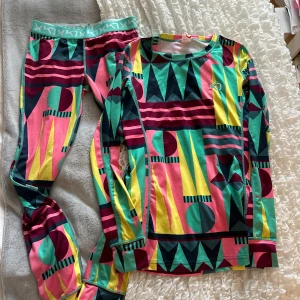 Färgglad långärmad underställströja från Kari Traa - Säljer en långärmad underställströja från Kari Traa med färgstarkt geometriskt mönster i rosa, gul, grön, vinröd och turkos. Perfekt för träning eller kalla dagar. Mjukt och stretchigt material.