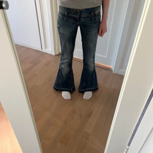 Low rise omsydda jeans från Diesel - Säljer ett par blå bootcut jeans från Diesel med slitna detaljer och nitar på bakfickorna. Jeansen är lågmidgade och i bra skick, endast använda få gånger. Har sytt om från skinny till bootcut. Köpte orginalt för 1000kr. Är 160cm lång 