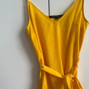 Linne med knytband - Senapsgult linne med knytband och slits på sidan.