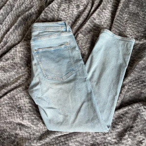 Ljusblå jeansbyxor från H&M - Ljusblå jeansbyxor från H&M med klassisk femficksdesign och regular fit. Byxorna har raka ben och normal midja, perfekta för en avslappnad stil. Tidlös modell som passar till många olika outfits. Dom är aldrig använda. Bara att höra av sig om fler bilder eller funderingar.