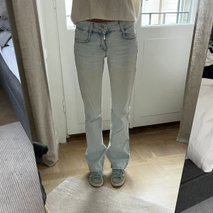 Ljusblå jeansbyxor från Pull&Bear - Säljer ett par ljusblå jeansbyxor från Pull&Bear med klassisk femficksdesign och normal passform. Storlek 34. Sitter snyggt och är i fint skick. Jag är 169 cm lång, och på bilderna är mitt innerbensmått ca 82,5 cm och midjemått (platt mätt på mig) ca 31 cm.