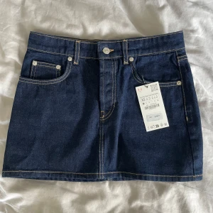 Mörkblå jeanskjol  - Säljer en mörkblå jeanskjol från Zara då den tyvärr inte passar mig. Helt oanvänd med lappen kvar. Storlek XS, midjemått 36 cm och längd 33,5 cm. Perfekt till sommaren 💙💙