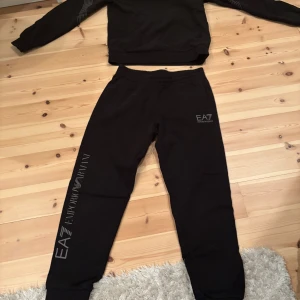 Tracksuit Emporio Armani EA7 - Säljer en Armani tracksuit i storlek 152 cm.🤩 Den är använd för några år sedan när jag var mindre men den är i perfekt skick👍‼️Nypris 1200 kr mitt pris 350 kr🚨Om det är något ni undrar skriv till mig jag svarar snabbt⁉️