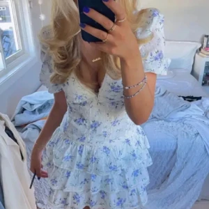 Vit blommig volangklänning - Supersöt kortklänning i blomstermönstet🥰 Passar perfekt till klänning skolavslutningen och jätte söt att ha i sommar! Vet ej va märket är! Priset kan diskuteras!