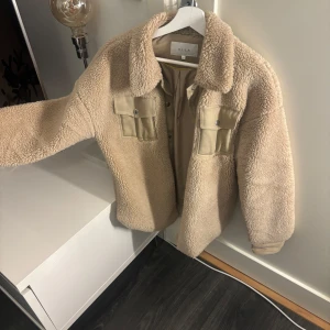 Beige teddyjacka från VILA - Hej!🩷Mysig beige teddyjacka från VILA med stora bröstfickor och knappar framtill. Jackan har klassisk krage och långa ärmar. Perfekt för lager-på-lager och ger en trendig look. Jackan håller en otroligt varm och har använts fåtal gånger. Jackan är felfri och pris kan diskuteras vid snabb affär. Nypris: 750kr. Säljer för: 300kr.🫶🏽