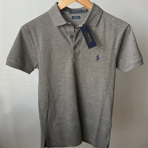 Polo Piké - Säljer denna stiliga Polo Ralph Lauren Piké! Perfekt nu till sommarn! Tröjan passade ej men är i helt nytt skick 10/10 med prislappen kvar! Storlek XS men kan även passa S. Hör av vid ytterligare frågor! Färgen är Grå!