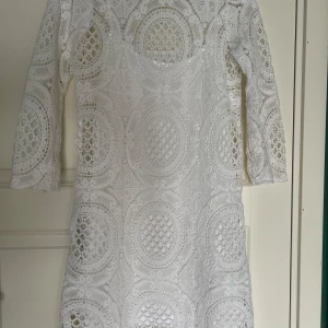 Vit spetsklänning från & Vintage Stories - Lite större i storleken, passar mig som är en typisk S.  Kommer med en innerklänning, axelbanden på denna är ej justerbara.   Använd max 1 gång, men jag tror aldrig jag använt den.   Ungefärliga mått enligt nedan:  Mått innerklänning 64cm ex axelband  Mått spets 86cm baktill på längsta stället  Ärmlängd 45cm