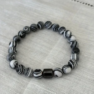 Pärlarmband med lavastenar - Coolt armband med lavastenar i olika färger och en blank svart pärla i mitten. Perfekt accessoar för dig som gillar stilrena och naturliga smycken. 49/st !!