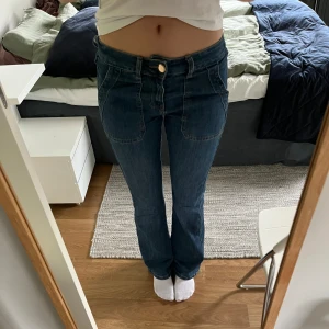 Blå bootcut jeans - Snygga blå jeans med bootcut passform och klassiska fickor både fram och bak. Jeansen har normalhög midja och stängs med knapp och dragkedja. Perfekta till vardags för en avslappnad men trendig look.