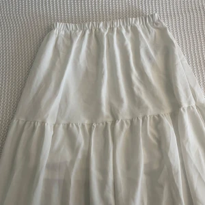Vit maxi kjol från Cider - Säljer en vit kjol från Cider i storlek M. Kjolen har volanger och resår i midjan för en bekväm passform. Tillverkad i 100% polyester och har en luftig känsla. Aldrig använt. Man ser inte igenom. 