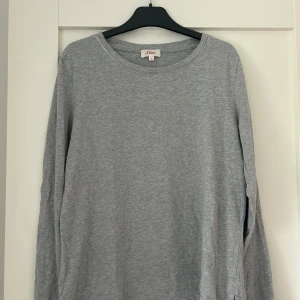 Grå långärmad tröja från S.Oliver - En enkel och stilren grå långärmad tröja från S.Oliver. Tröjan har rund halsringning och är tillverkad i mjuk bomull, perfekt för en avslappnad look. Köptes på Zalando förra året för 299 kronor.