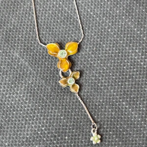 Pilgrim halsband med blommor - Säljer ett unikt halsband med silverkedja och två blommor Blommorna har glittrande stenar i mitten och en liten hängande blomdetalj längst ner. Perfekt för dig som gillar färgglada accessoarer!