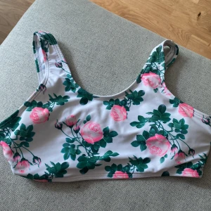 Blommig bikiniöverdel - Säljer en söt bikiniöverdel med blommigt mönster i rosa och grönt. Modellen har breda axelband och sportig passform, perfekt för strand eller pool eller för tex åka vattenrushkanor då bikini toppen inte åker ner.  Materialet är väldigt skönt och bekvämt😇