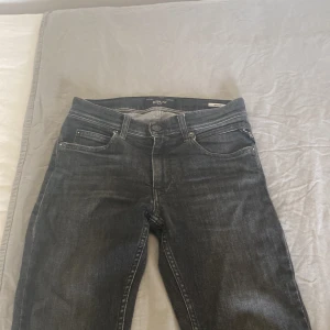 Svarta jeansbyxor från Replay - Säljer ett par svarta jeansbyxor från Replay med klassisk femficksdesign och slim ben. Jeansen har dragkedja och knapp. Perfekta till vardags och passar till det mesta. Defekter se bild 3/4, annars bra skick, kontakta vid frågor!