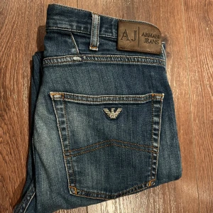Blå jeans från Armani  slim fit - Snygga blå jeans från Armani Jeans med klassisk femficksdesign och logotyp på bakfickan. De har en straight passform och är tillverkade i slitstarkt denim. Perfekta för en stilren look. Storlek W32 L32