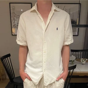  Polo Ralph Lauren linneskjorta - Säljer nu denna vita klassisk kortärmad skjorta från Polo Ralph Lauren i linne. Skjortan är i fint skick utan några skavanker. Perfekt för varma dagar. Hör gärna av er med frågor och funderingar. 