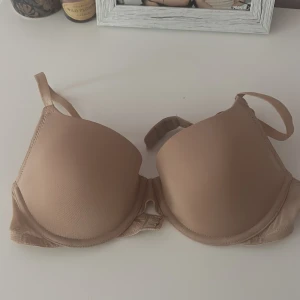 Beige bh från H&M - Säljer en beige bh från H&M med släta kupor och justerbara axelband. Bh:n har en enkel och stilren design, perfekt under ljusa toppar. Materialet är mjukt och bekvämt med en liten andel elastan för stretch.
