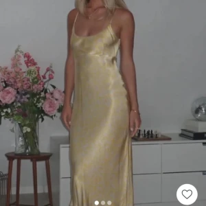 Ljusgul långklänning Ganni - Säljer en elegant ljusgul långklänning i satin med smala axelband och blommigt mönster i gult. Klänningen är Ganni, säljs inte längre. (Bilderna är lånade) 