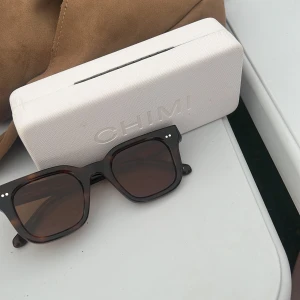 Bruna solglasögon från CHIMI - Snygga solglasögon från CHIMI i modellen Tortoise med fyrkantig form och mörkbruna glas. Bågarna har en klassisk brunmelerad färg och passar perfekt för dig som gillar stilrena accessoarer.