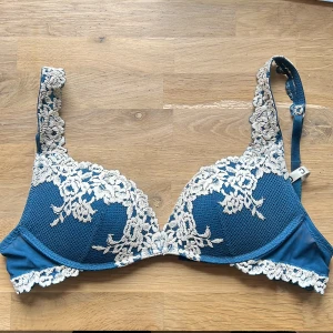 Blå push up-bh från intimissimi - Säljer en blå push up-bh Gioia från Intimissimi med vacker vit spetsdetalj över kuporna och axelbanden. Bh:n har justerbara axelband och en mjuk, bekväm känsla. 
