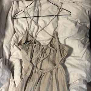 Ljus långklänning med smala axelband från & Other Stories - Säljer en ljus långklänning från & Other Stories med smala korsade axelband och lätt rynkad midja. Klänningen har en enkel och stilren design, perfekt för varma dagar. Materialet känns mjukt och luftigt.