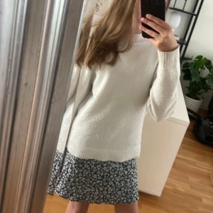 Blommig kort kjol från H&M Divided - Supersöt kjol från H&M Divided med svart bakgrund och små vita och blåa blommor. Kjolen har en lätt och luftig känsla, perfekt för varmare dagar. Passar dig som gillar en feminin och avslappnad stil.