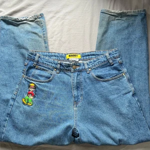 bass baggy jeans från butter goods - Säljer ett par Butter Goods Bass Baggy Jeans i storlek 32. Klassisk baggy passform i tvättad blå denim med broderad grafik fram (bild 3). Använda men i okej skick, lite slitage/blekning vid nederkanterna (se bild 5), annars hela och fina.