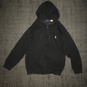 Ralph Lauren tröja  - Nu säljs det en helt ny. Oanvänd. Svart Ralph Lauren tröja. Tröjan har en dragkedja där fram och märke vid bröstet. Det är storlek S men passar mer som XS. Pris kan självklart diskuteras.