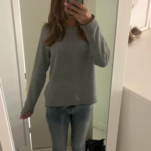 Grå stickad tröja med rund hals - Mysig grå stickad tröja med rund halsringning och långa ärmar. Tröjan har en enkel och stilren design. Jätte mysig nu till hösten🍁