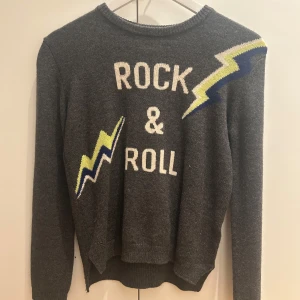 Grå stickad tröja Zadig & Voltaire - Skit cool grå Zadig Voltaire tröja som är stickad och mjuk med texten rock & roll! Perfekt för att göra en outfit ännu snyggare. Den är helt oanvänd💕