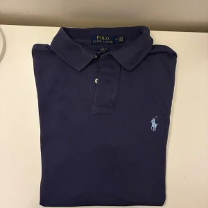  Polo Ralph Lauren piké - Snygg marinblå piké från Polo Ralph Lauren i slim fit-modell. Storlek M. Skriv vid frågor eller funderingar.