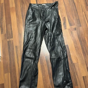 Svarta skinnbyxor från NLY Trend - Snygga svarta skinnbyxor från NLY Trend i storlek 36. Byxorna har raka ben, bälteshällor och klassisk femficksdesign. Perfekta för dig som vill ha en edgy look med stilren känsla. Nyskick! 