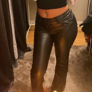 Svarta bootcut byxor i skinnimitation - Säljer ett par svarta bootcut byxor i skinnimitation med låg midja. Byxorna har klassiska fickor både fram och bak och sitter tight upptill med utsvängda ben. Vet ej vart jag har köpt de, har även klippt längden själv. Kontakta om du vill ha fler bilder!❤️