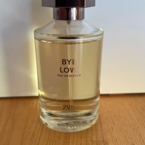 ZARA Bye Love Eau de Parfum - Fräsch parfym från ZARA i modellen Bye Love. Flaskan är genomskinlig med en stilren, rund form och har ett silvrigt lock. Parfymen har en ljusgul ton och flaskan är i glas med minimalistisk design. Perfekt för dig som gillar moderna dofter.