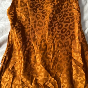 Leopardmönstrad satin klänning - satin klänning med leopardmönster i färgen orange-brun . 