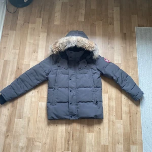 Grå dunjacka med pälskrage från Canada Goose - Säljer en grå dunjacka från Canada Goose med huva och pälskant. Pris kan sänkas 