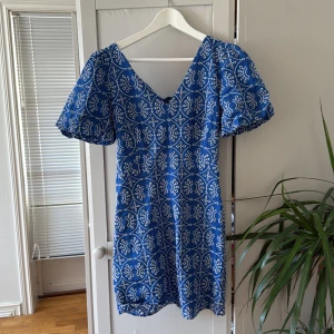 Blå kortklänning med vit broderad mönster - Fin klänning som passar perfekt till sommaren!