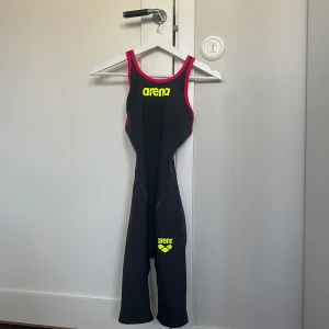 Arena tävlingsbaddräkt  - Tävlingsbaddräkt från arena. I använt skick. Defekter: ett hål vid limningen på benet, går att limma ihop. Limningarna på hela baddräkten är slitna. Perfekt slit och släng baddräkt för exempelvis träning. Baddräkten är i storlek UK 30 (se bild). Säljes då jag slutat simma. Säljes för 500 kronor. Priset går såklart att diskutera.