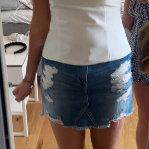 Blå jeanskjol från Hollister - Säljer en blå jeanskjol från Hollister med slitna detaljer. Står W25, skulle säga att den passar S/Xs beroende på hur man vill ha den 