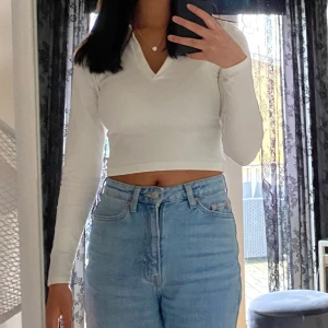 Vit croppad ribbad långärmad topp från Stradivarius - Säljer en vit croppad långärmad topp från Stradivarius. Tröjan har ribbad struktur, v-ringning och klassisk krage. Bra kvalitet med tanke på att den inte nopprar sig så mycket och att det är tjockt. Jag är S/M i storlek.