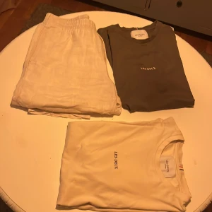 Vit t-shirt från Les Deux och linnebyxor - En liten sommar bulk 2 snygga t shirts och 1 par linne byxor. Vit t-shirt från Les Deux med enkel och stilren design. T-shirten har rund halsringning och korta ärmar. Perfekt för en clean och avslappnad look. 