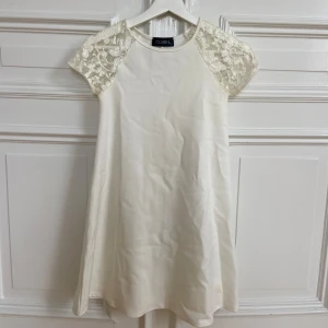 Examensklänning- Vit klänning med spetsärmar från Club L - Säljer en söt vit klänning från Club L med korta ärmar i spets. Klänningen har en rak passform och är tillverkad i ett mjukt tyg som känns bekvämt. Perfekt för somriga tillfällen eller studentfirande.