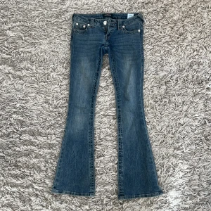 Lågmidjade bootcut jeans från True Religion - Säljer mina blåa lågmidjade bootcut jeans True Religion då de inte kommer till användning. Storleken är 23 men är samma som xs/s. De är lite slitna där nere på byxorna då de är lite för långa för mig och har trampat på dem därav priset men det är inget som märks av. Skriv för mått eller fler bilder! 