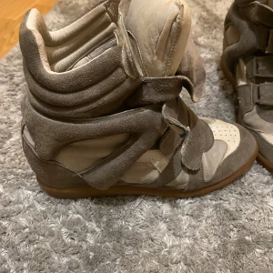 Isabel marant wedge sneakers - Isabel Marant skor kilklackar beige/gråa. Finns små fläckar som syns på nära håll men svårt att se på avstånd. Skorna är äkta men har tyvärr inte lådan eller dustbag. Skorna är i storlek 40. Pris går självklart att diskuteras!