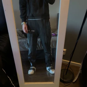 Palm angels byxor  - Palm Angels Track Pants – Original Säljer mina äkta Palm Angels track pants, en riktig streetwear-klassiker! Byxorna har den ikoniska designen med logga framtill och kontrasterande stripes längs benen. Sköna att ha på sig och samtidigt riktigt snygga – perfekta både till vardags och fest.                                                                         Hör av dig för fler bilder eller exakta mått