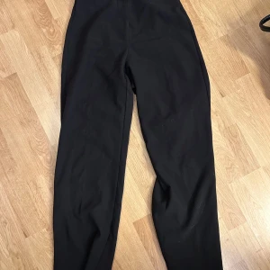 Svarta kostymbyxor från Vero Moda - Svarta kostymbyxor från Vero Moda med hög midja och rak passform. Byxorna har en diskret dragkedja på framsidan.💖