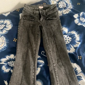 Grå bootcut jeans från Nelly, stl 32 - Snygga grå bootcut jeans från Nelly med låg midja och stora fickor fram. Använd en gång