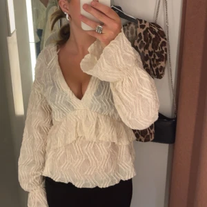 Vit blus med volang och v-ringning - Säljer denna super snygga blus från Gina då den inte kommer till så mycket användning. den är i super bra skick. Storlek S
