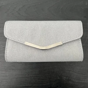 Silverfärgad glittrig kuvertväska - Säljer en snygg silverfärgad kuvertväska med glittrig yta och metallspänne framtill. Väskan har en kedja så den kan bäras över axeln och ett fack på insidan för småsaker. Perfekt till balen